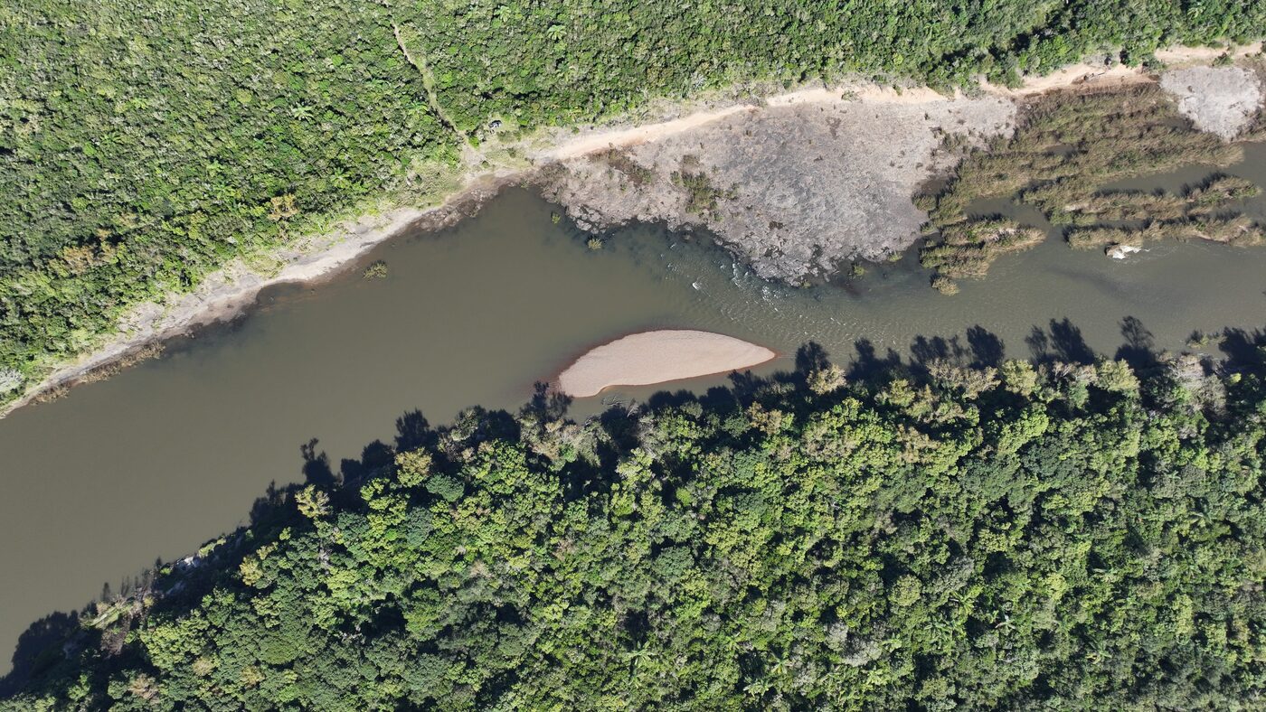 Rio e banco de areia margeados por mata nativa, vistos do alto